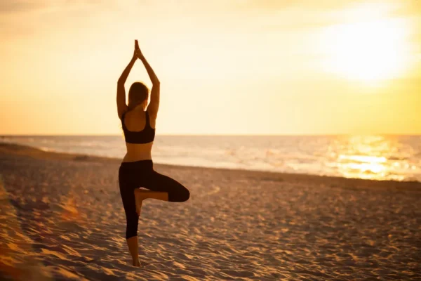 A woman is doing yoga on the beach