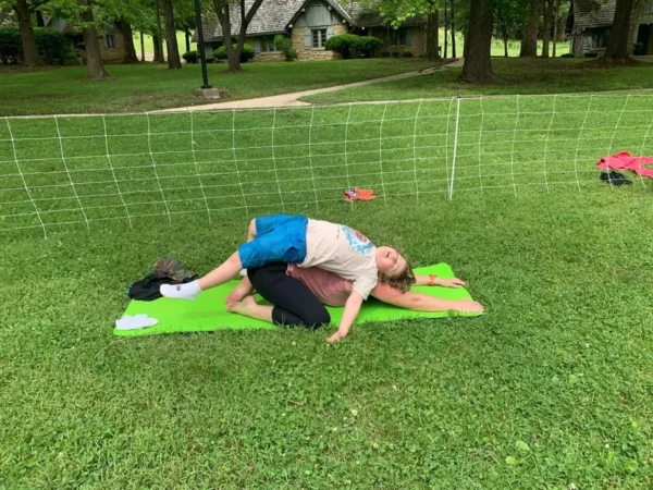 A man and woman are doing yoga in the grass.