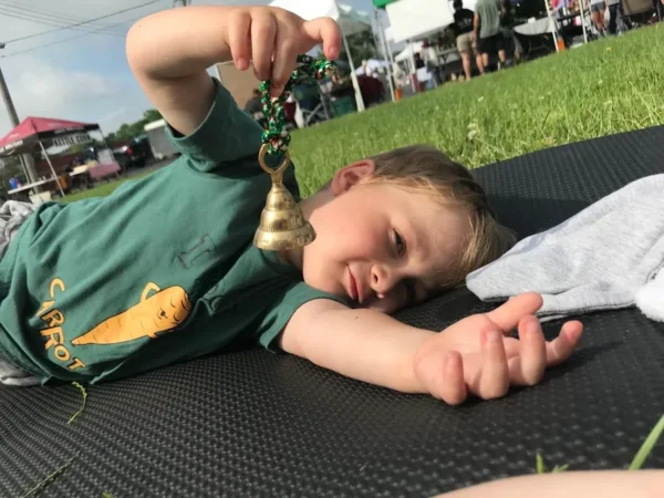 A young boy laying on the ground holding a phone.