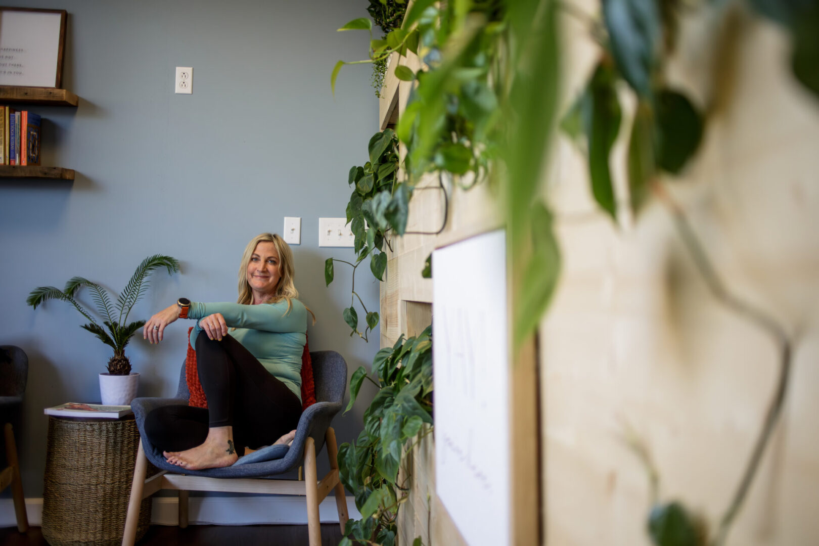 A woman sitting on top of a chair in front of some plants.